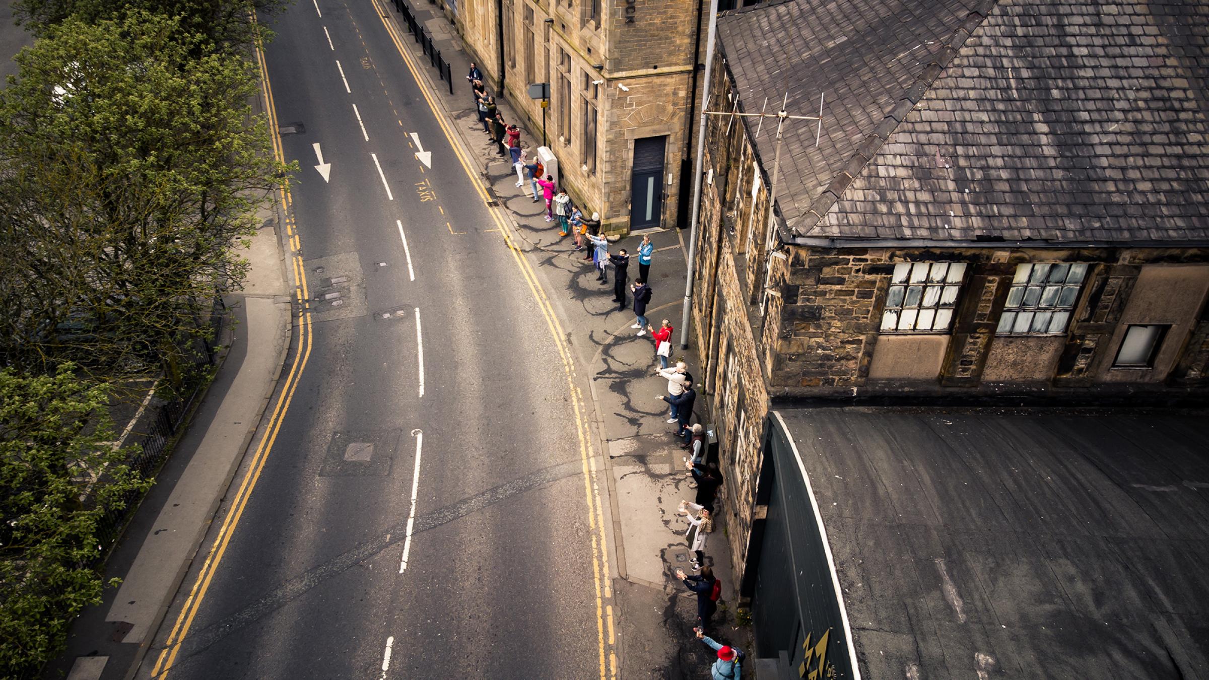 Aerial shot of people standing in a line on a pavenment