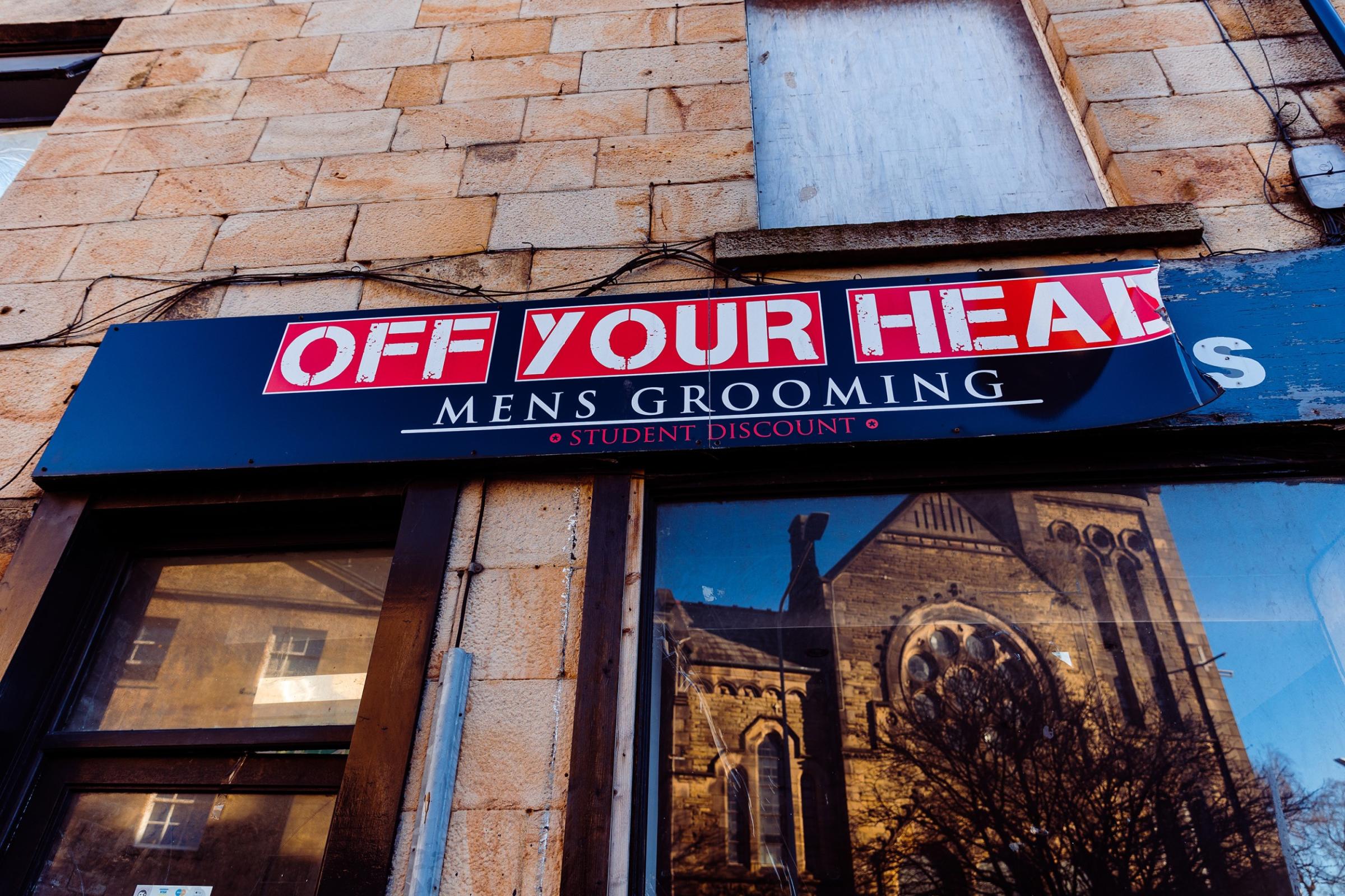 Image of a shop front called Off Your HEad Mens Grooming with the reflection of an old church in the window
